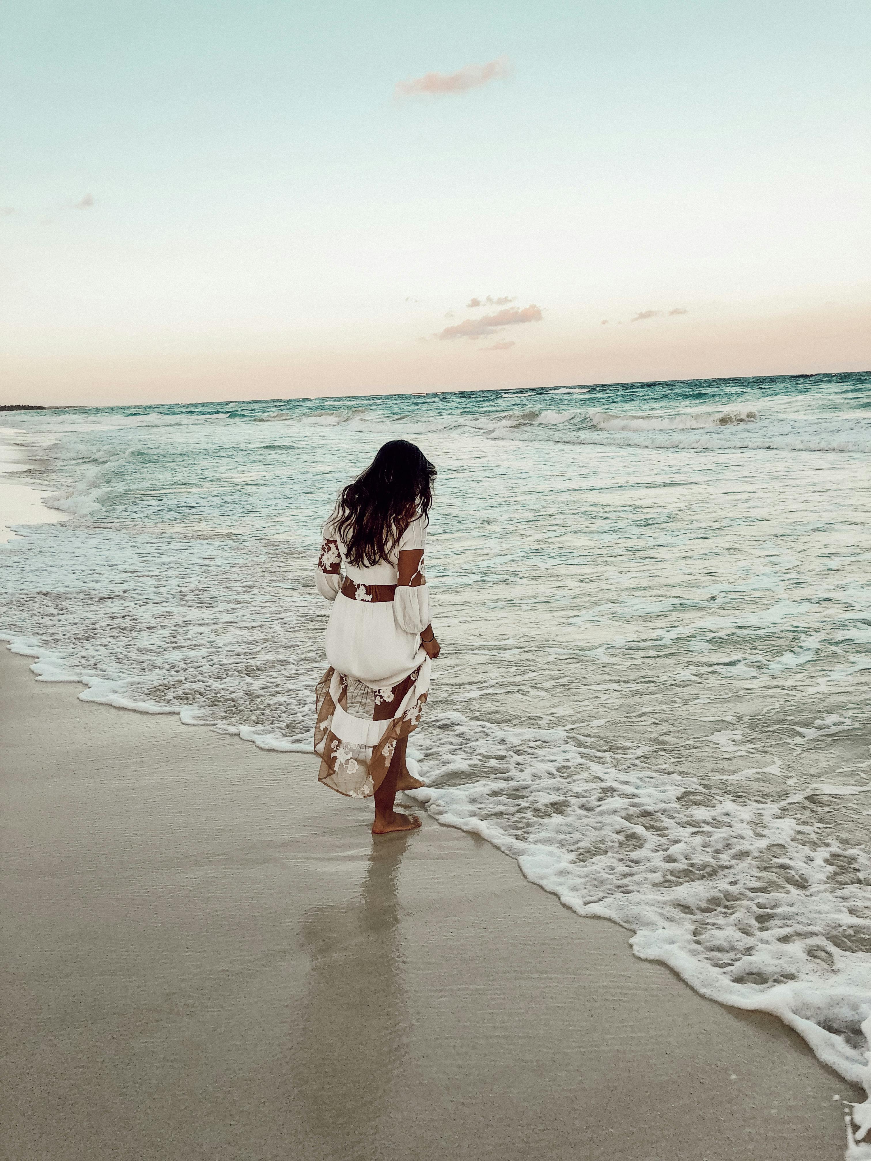 Woman walking alone on a quiet beach at sunrise