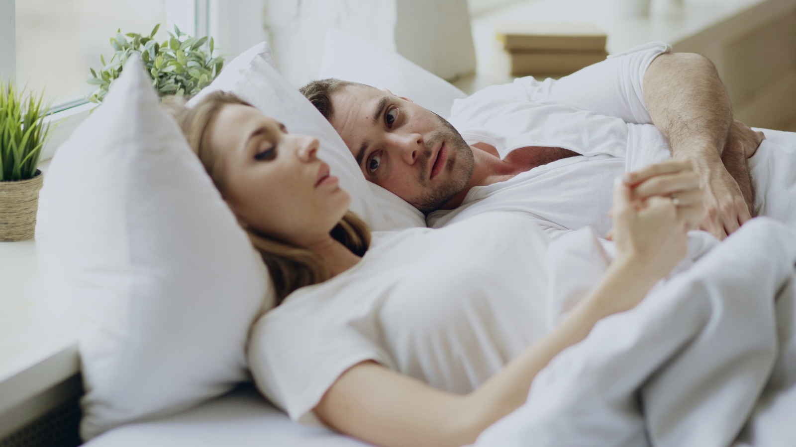 couple laying in bed thinking about their marriage.
