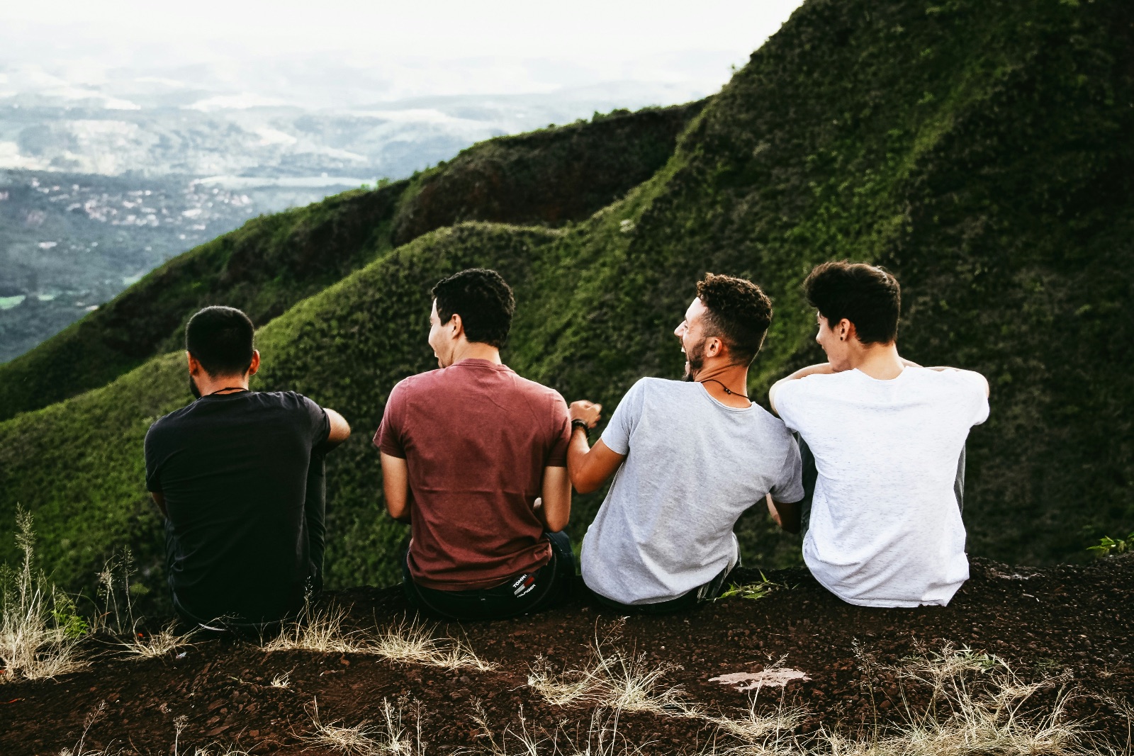 Four men sitting together on a mountain top enjoying the view.