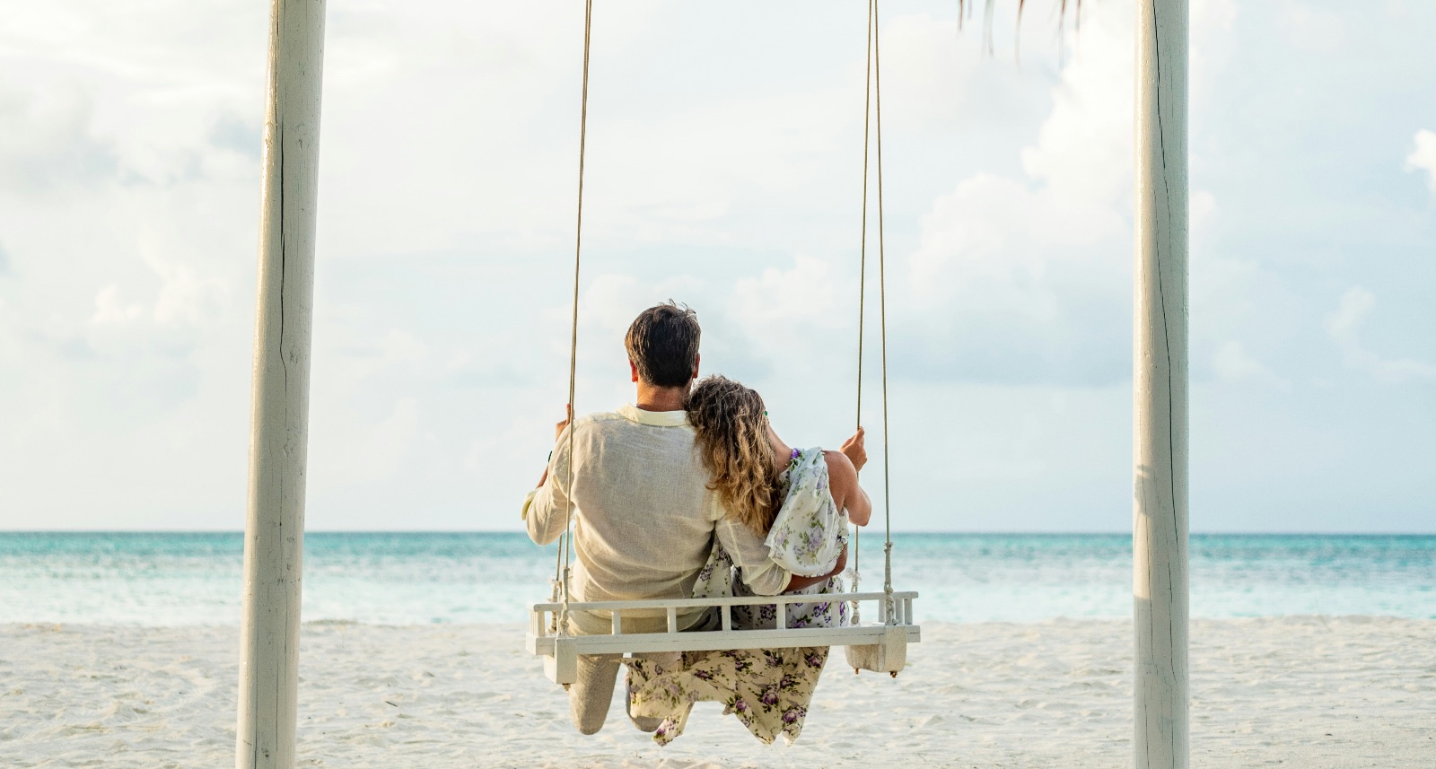Couple on a swing together on the beach.