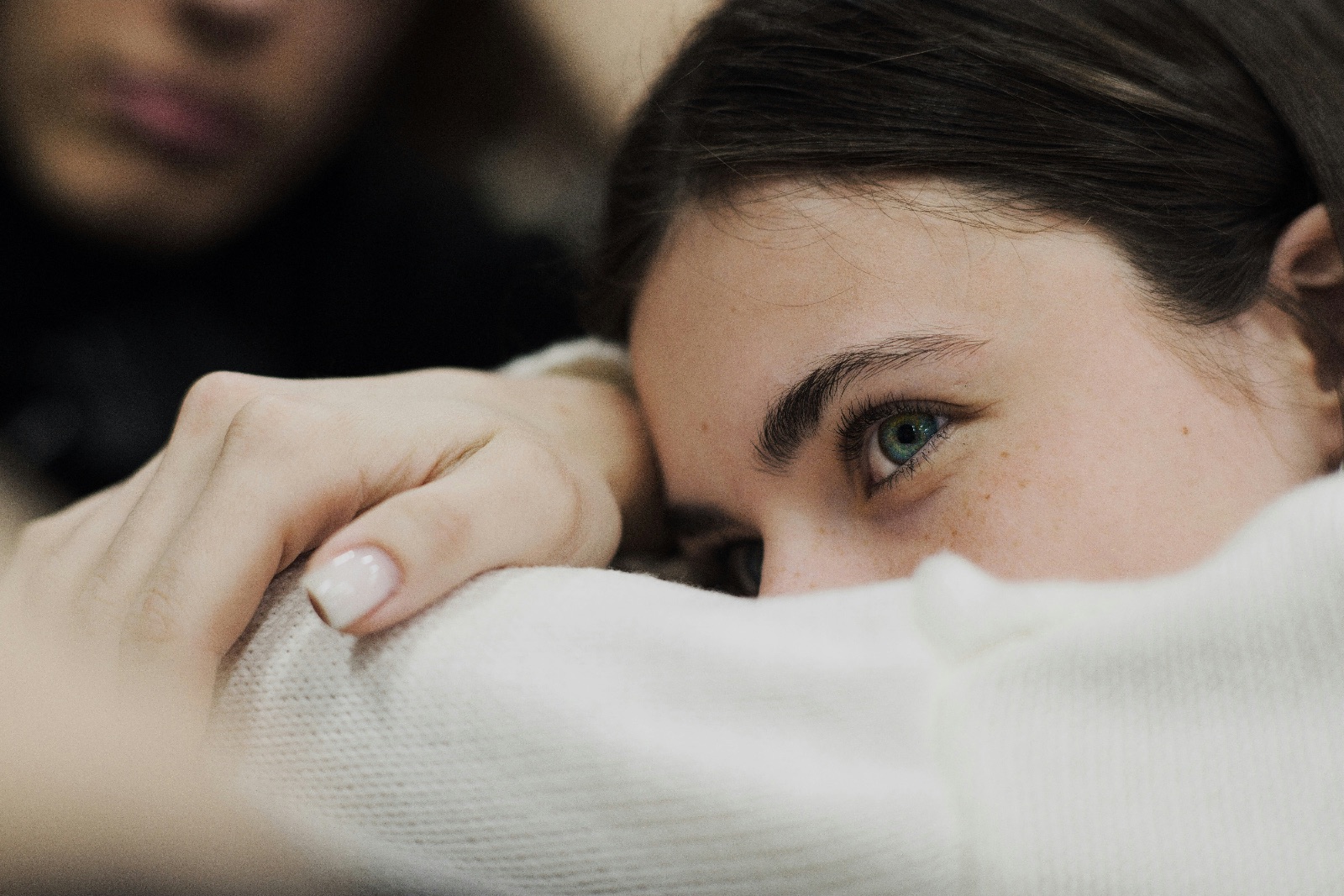 A woman sits quietly beside her husband after a difficult conversation, looking hurt and emotionally disconnected.